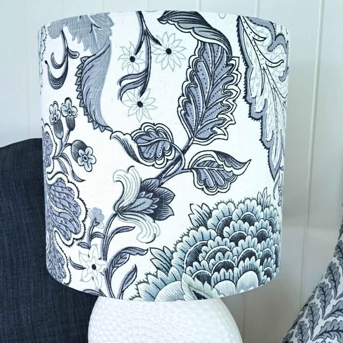 White textured vase with a floral-patterned lampshade on a wooden surface.