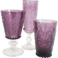 Set of three purple glass goblets with intricate designs on a white background