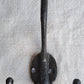 Black metal double hook with a ruler for scale on a gray background