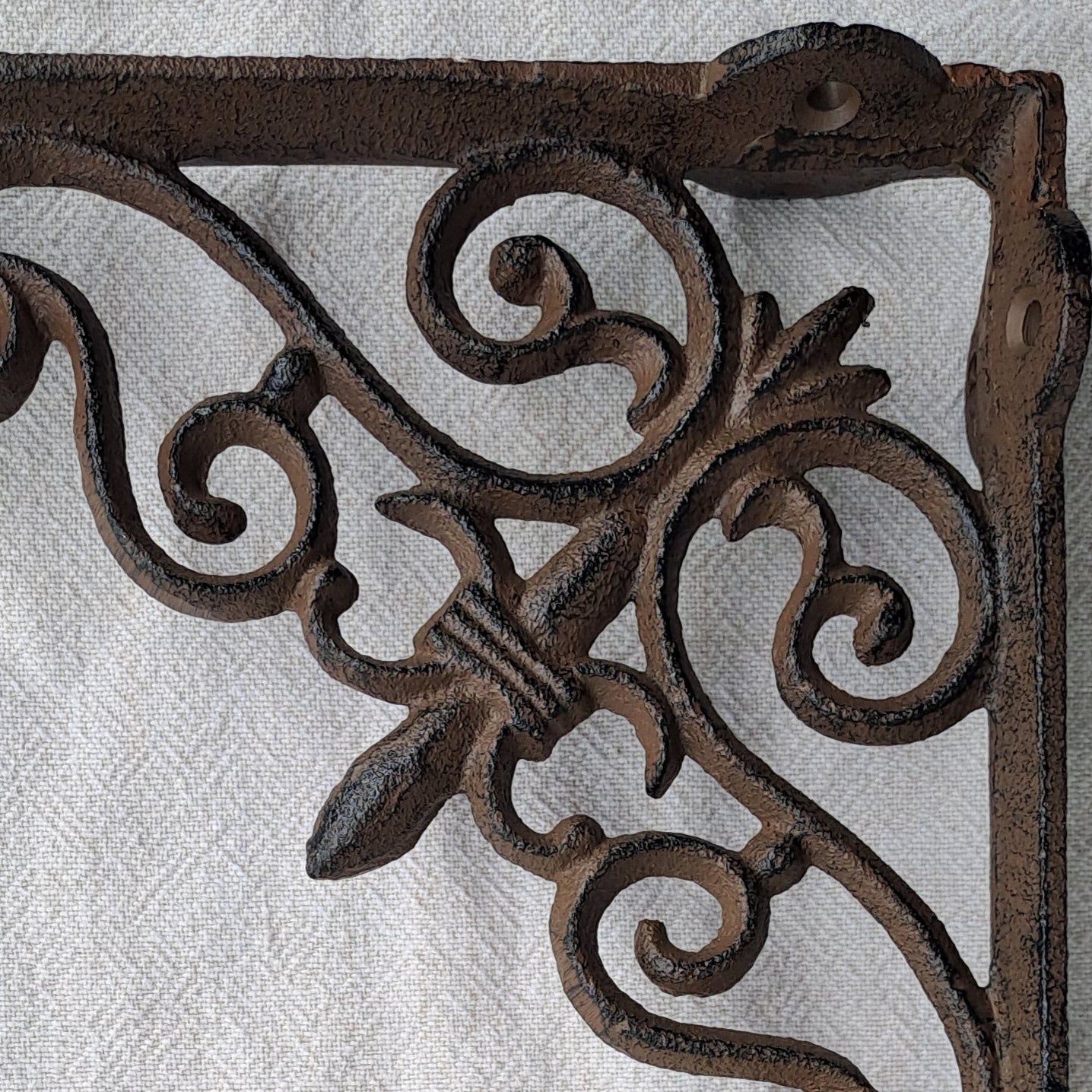 Decorative wrought iron bracket on a white fabric background