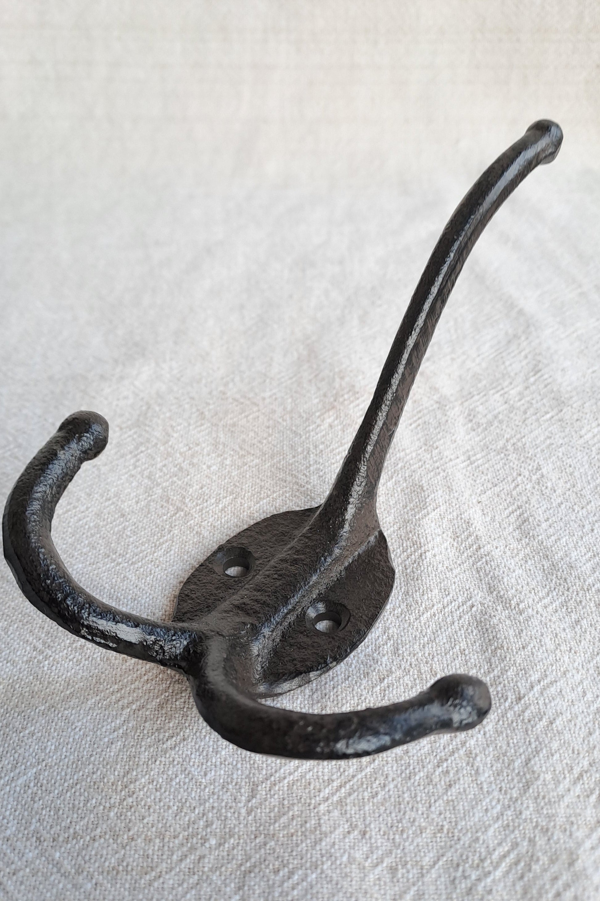 Black metal double hook on a textured beige background