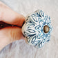 Hand holding a ceramic knob with blue and white pattern