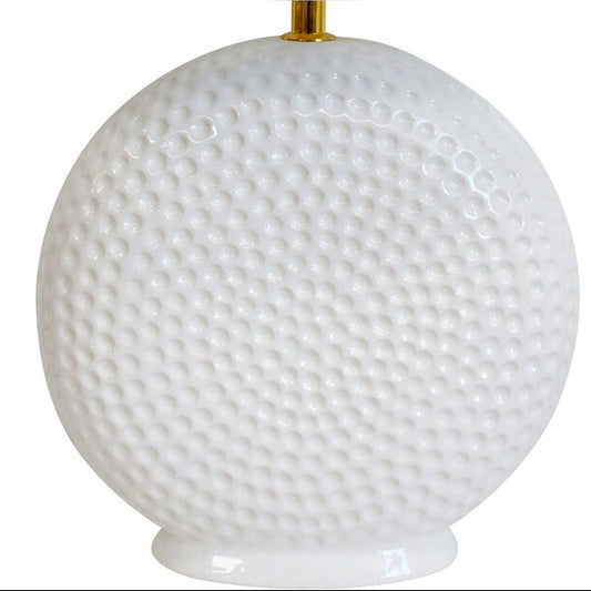 Table lamp with textured white base and beige lampshade on a white background