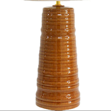 A table lamp with a textured, ribbed brown ceramic base and a cylindrical off-white fabric shade, shown illuminated against a plain white background.