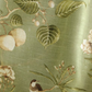 Fabric with bird and floral pattern held by hands on a green background