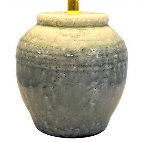 Table lamp with a textured ceramic base and white shade on a white background