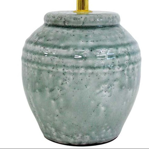 Table lamp with a textured ceramic base and white shade on a white background