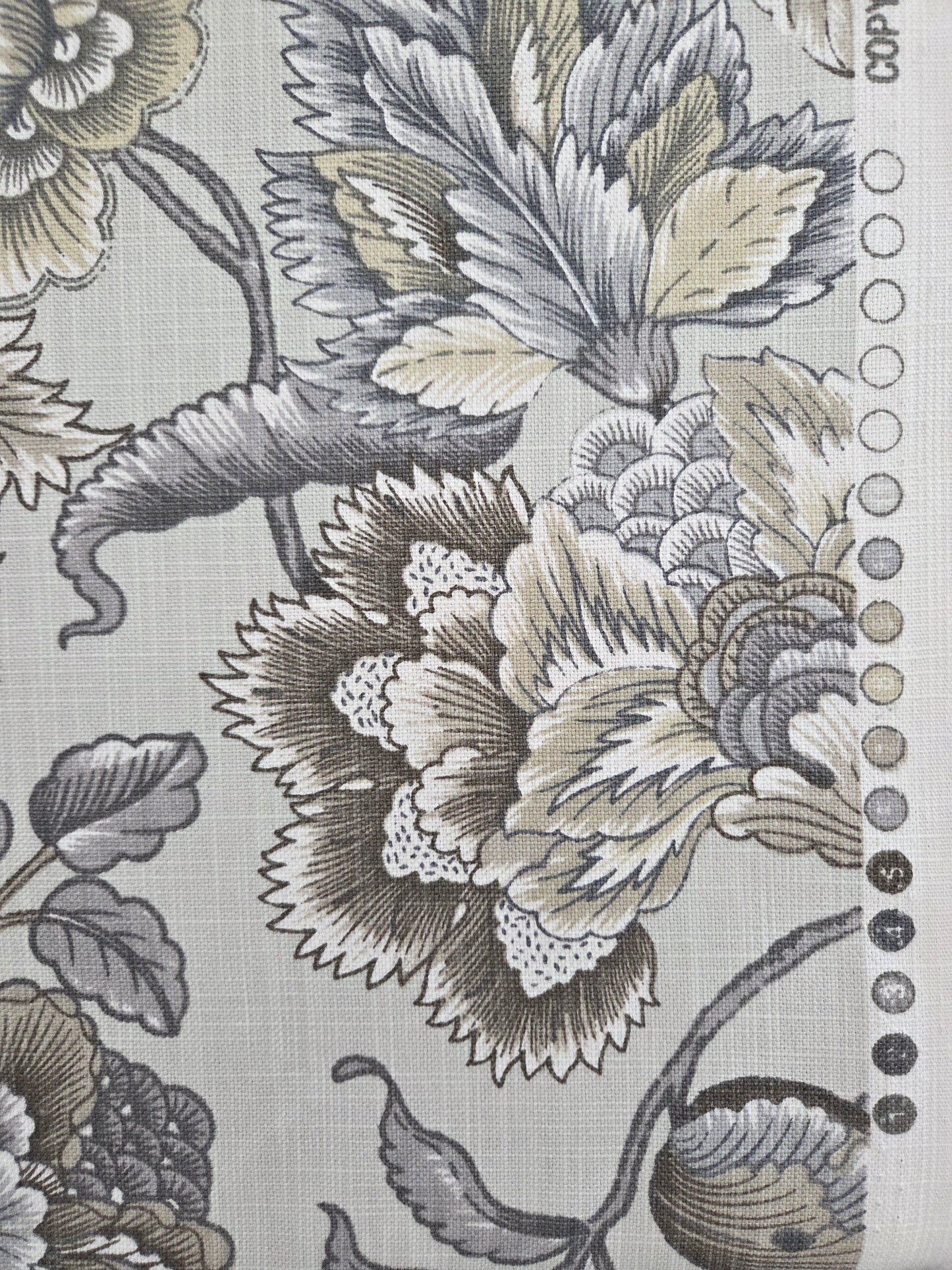 A close-up of a fabric or wallpaper pattern featuring large floral motifs in gray, beige, and black on a light gray background, with a row of small circular color swatches along the top edge.