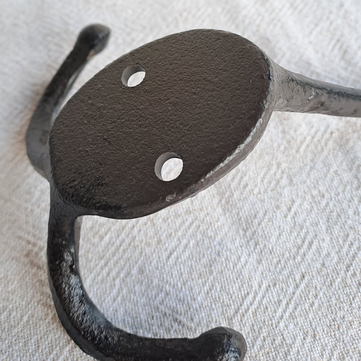 Black metal double hook on a textured white background
