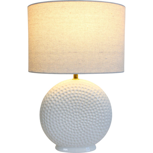 Table lamp with textured white base and beige fabric shade on a white background